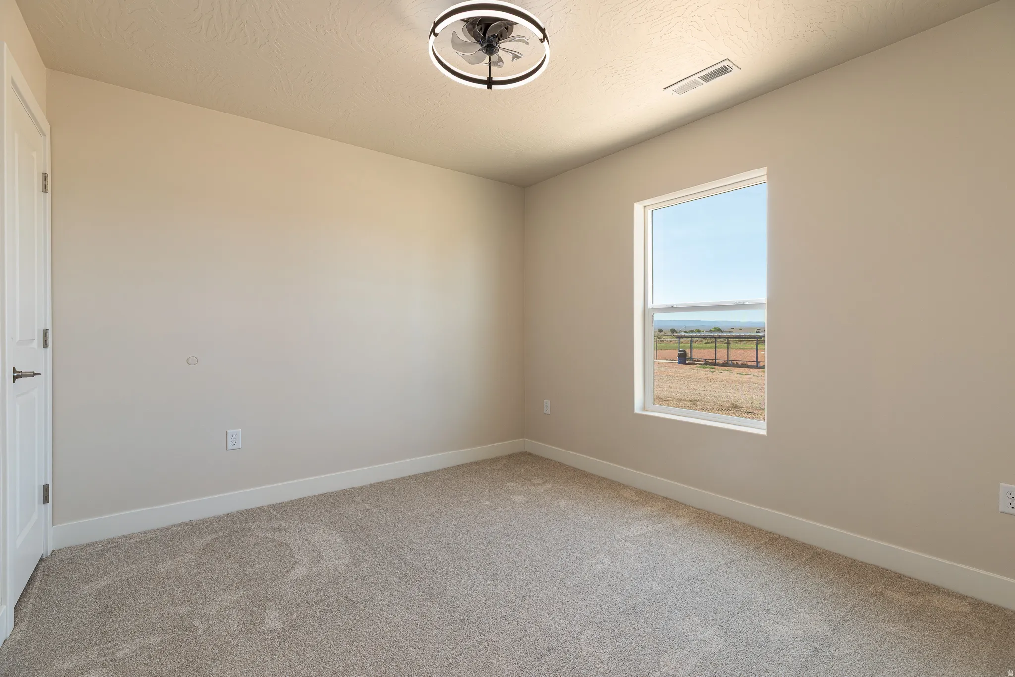 Spacious room featuring neutral carpeting, light neutral wall paint, and white trim