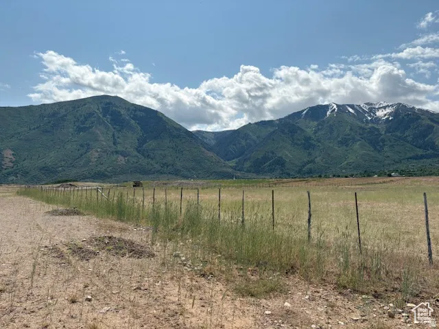 Expansive land parcel featuring a rustic fence line and a mountainous backdrop