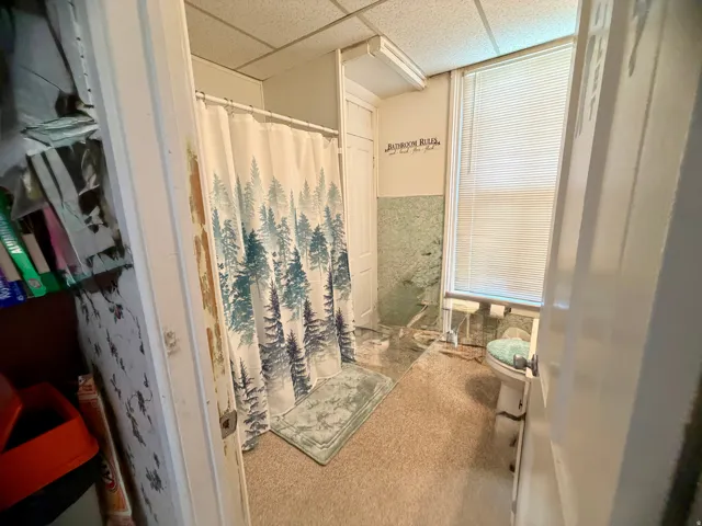 Bathroom featuring a shower stall, window with blinds, and wall-mounted lighting