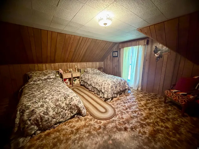 Room featuring wood-paneled walls and a textured drop ceiling