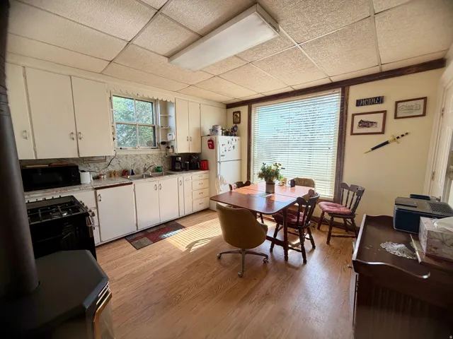 Kitchen space featuring a wood-finish flooring, white cabinetry, a built-in oven range, and a drop ceiling with fluorescent lighting