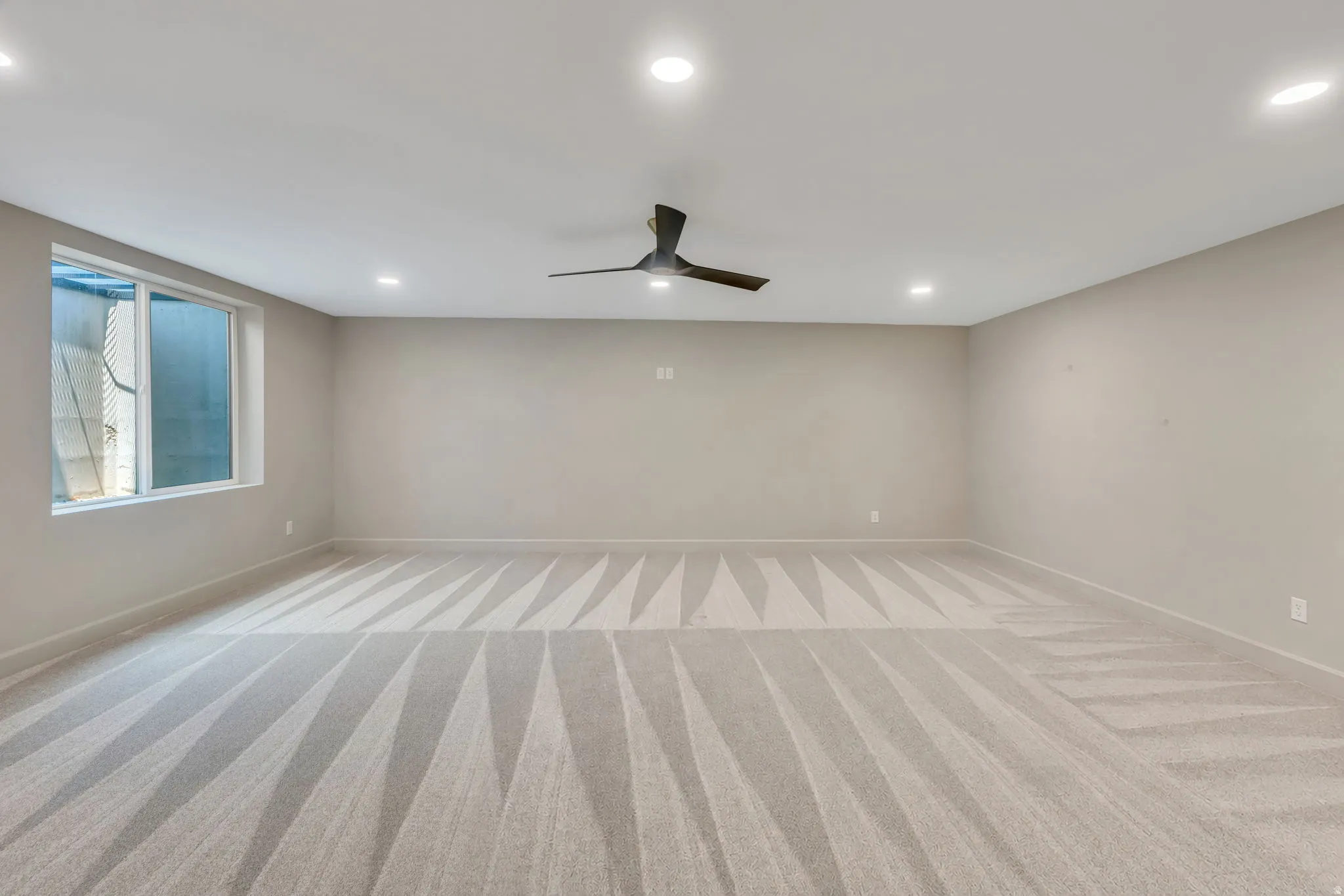 Spacious room featuring carpeting, recessed lighting, a contemporary ceiling fan, and a large window