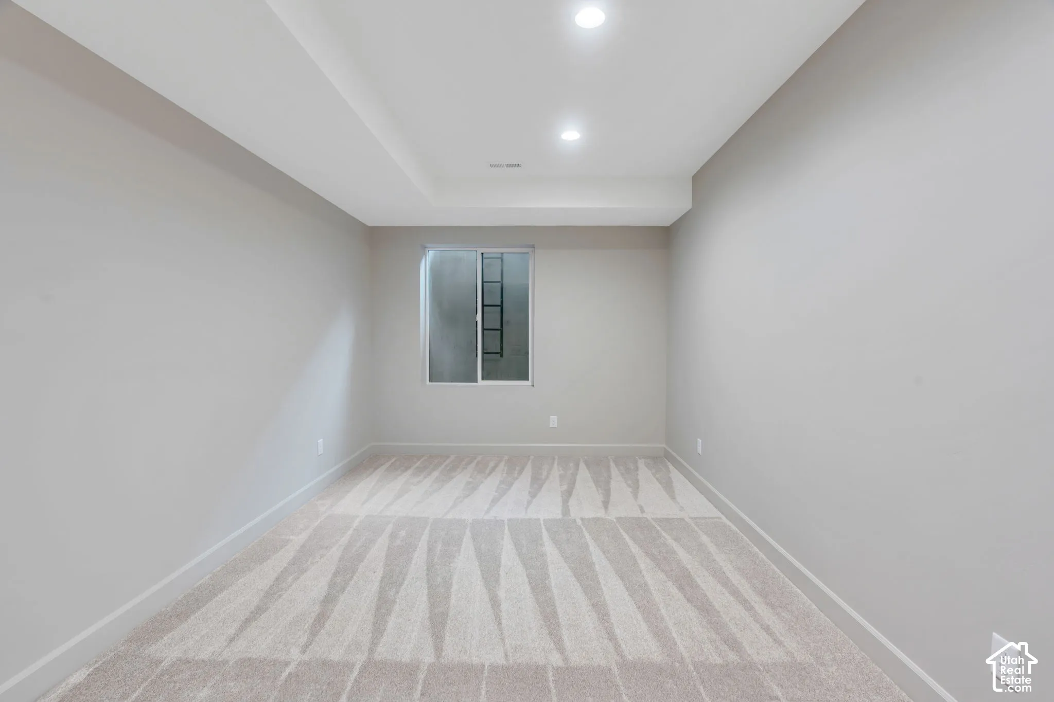 Neutral-toned room featuring a single window, recessed lighting, and carpet flooring