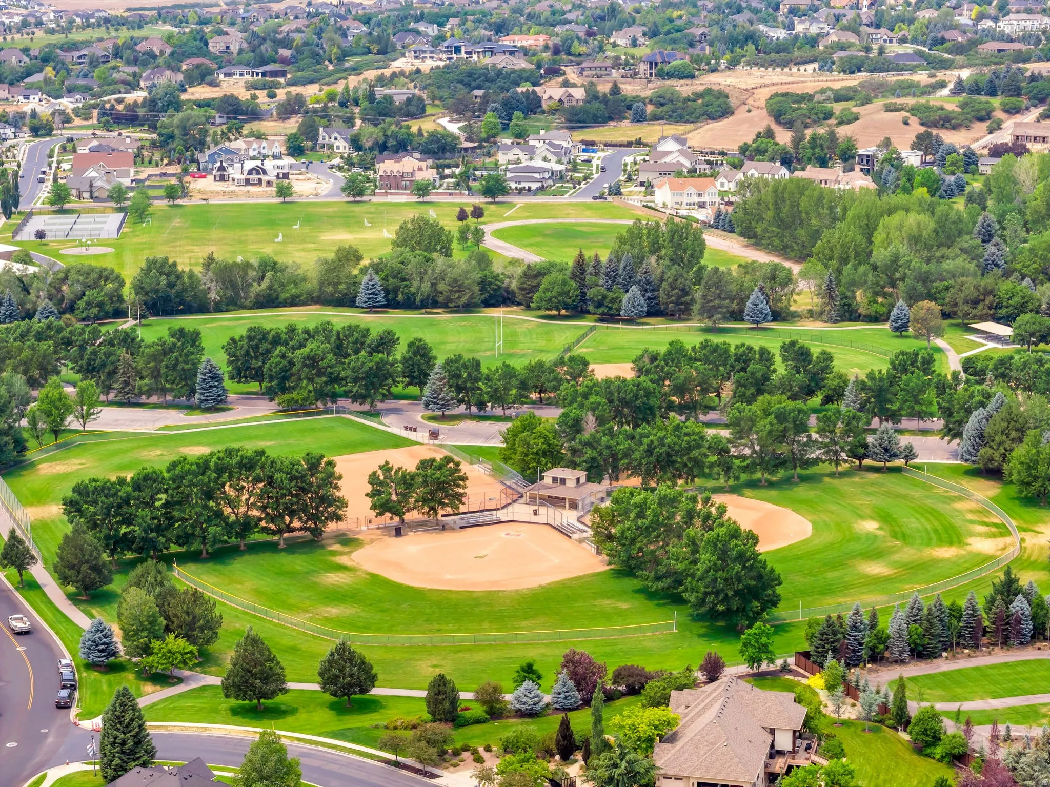 Expansive green spaces featuring multiple baseball fields, surrounding walking paths, and mature trees in nearby Burgess Park