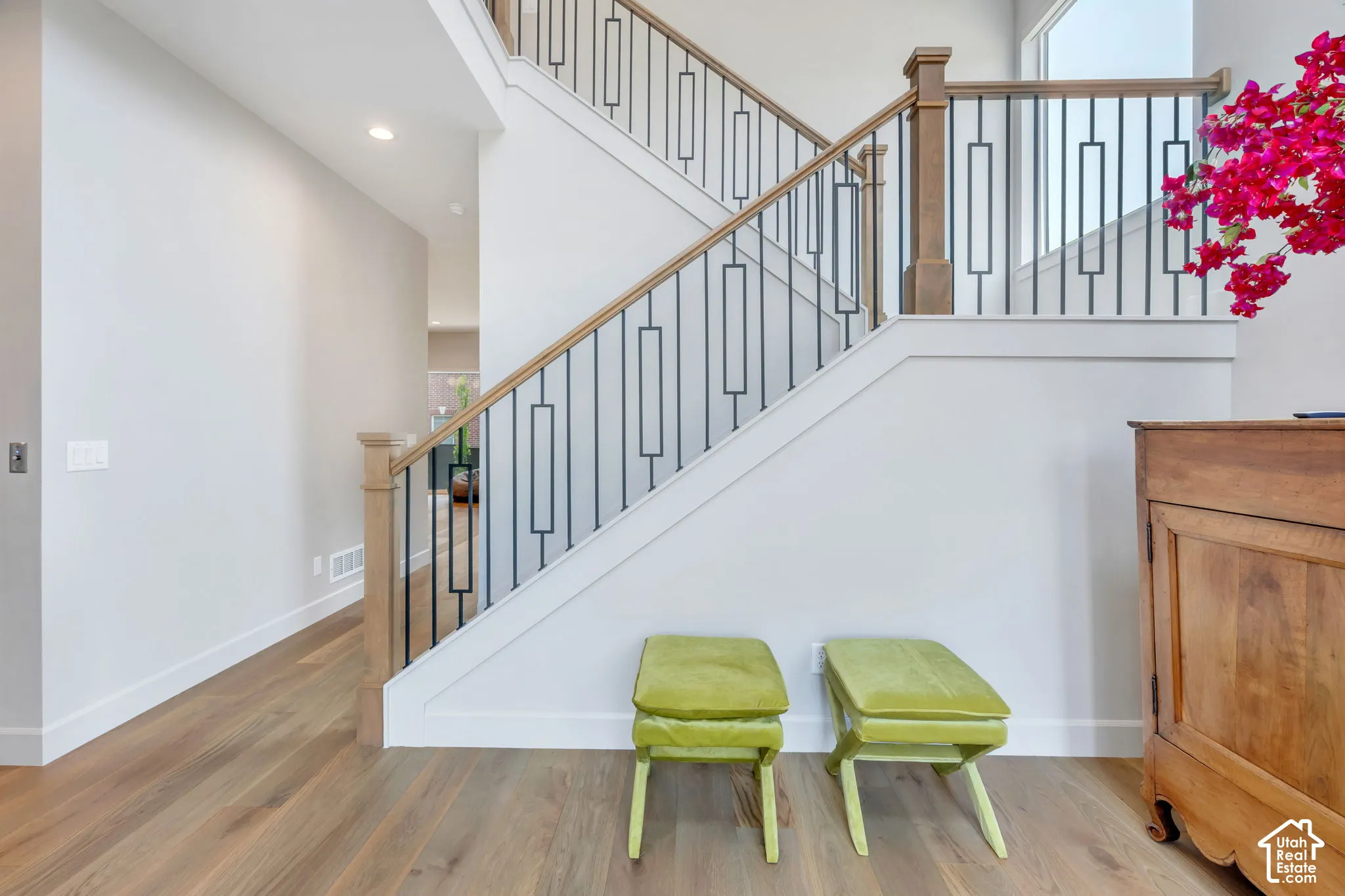 Entryway featuring light wood-finish flooring, white baseboards, and a staircase with a natural wood handrail and black metal balusters
