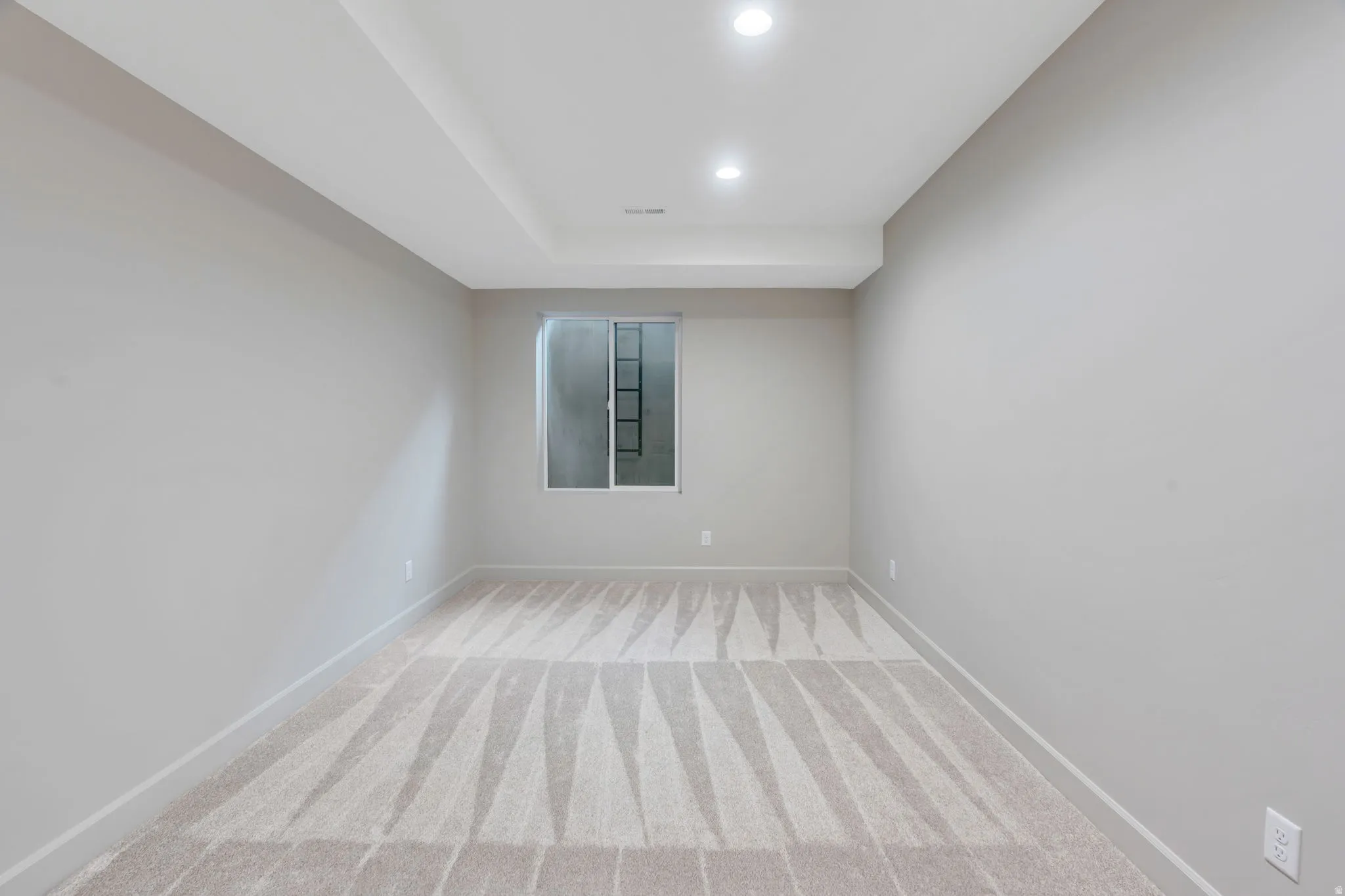 Neutral-toned room featuring a single window, recessed lighting, and carpet flooring