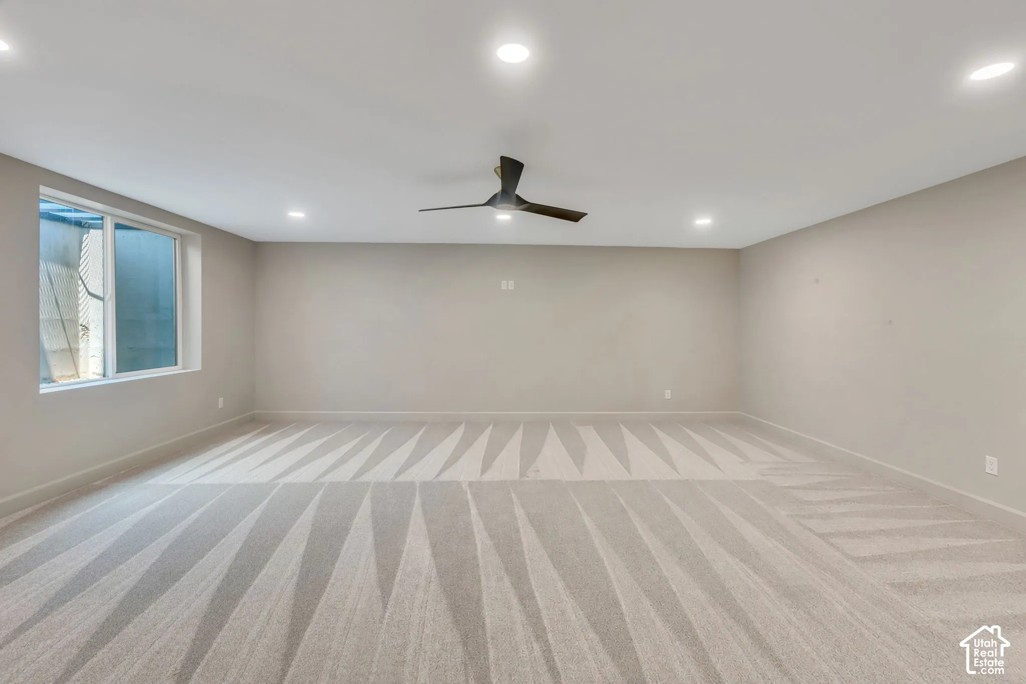 Spacious room featuring carpeting, recessed lighting, a contemporary ceiling fan, and a large window
