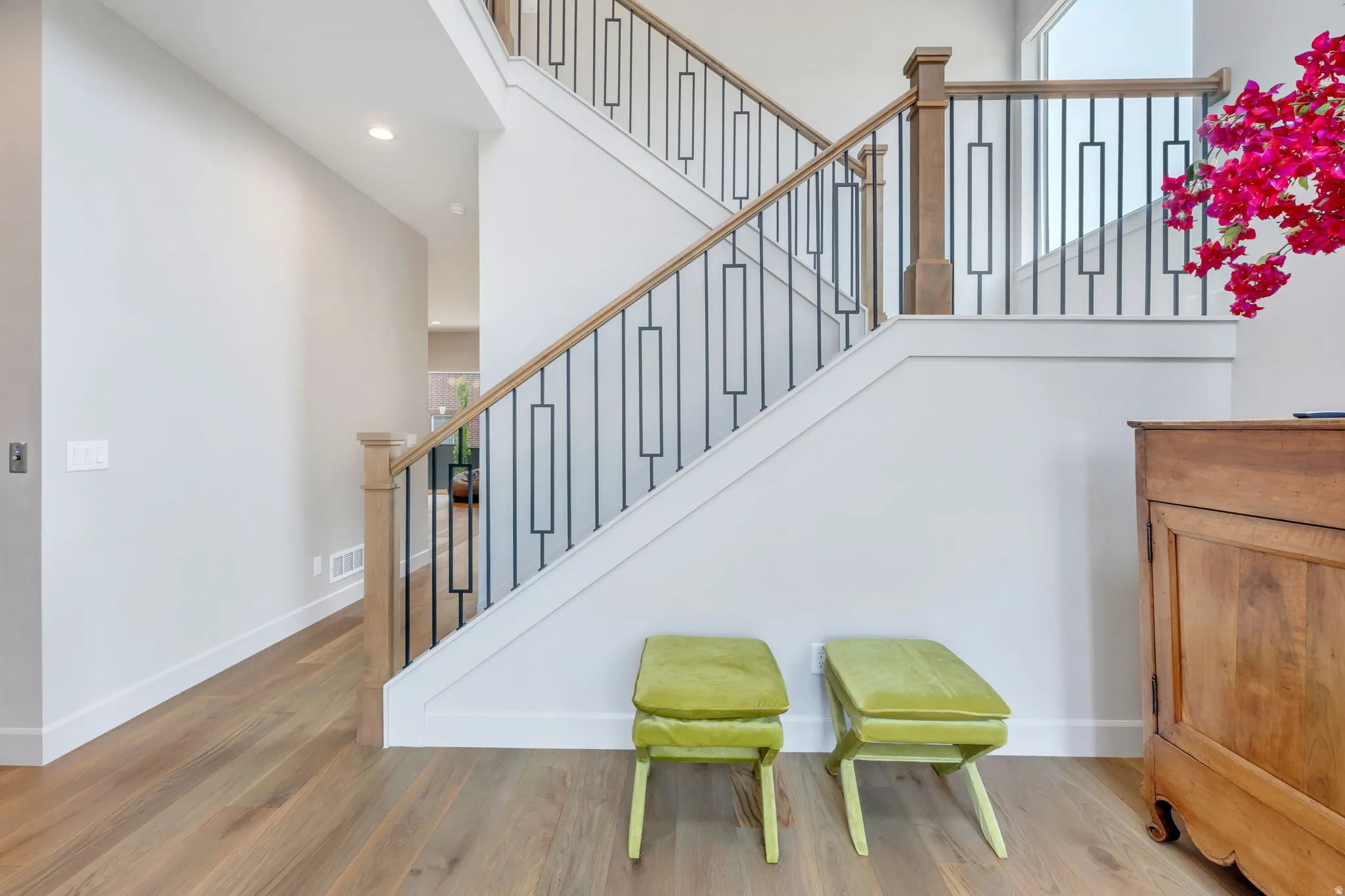 Entryway featuring light wood-finish flooring, white baseboards, and a staircase with a natural wood handrail and black metal balusters