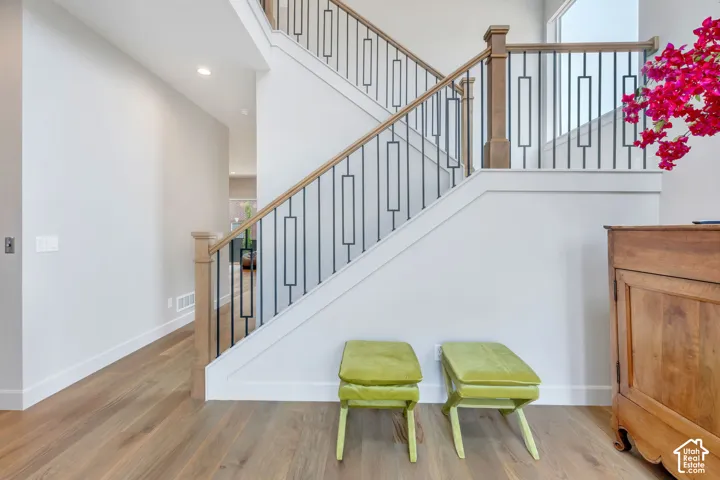 Entryway featuring light wood-finish flooring, white baseboards, and a staircase with a natural wood handrail and black metal balusters