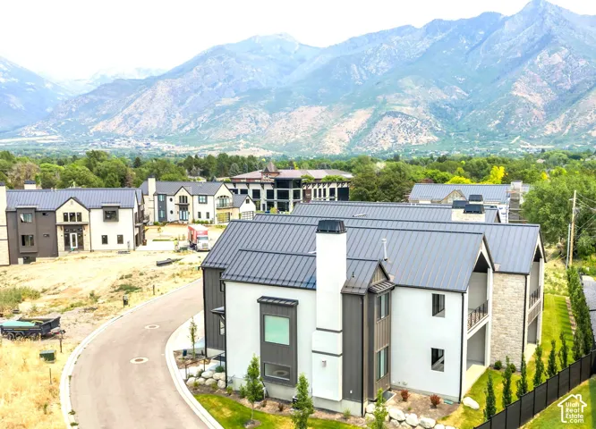 Modern residential structures featuring light-colored siding, dark metal roofs, and stone accents