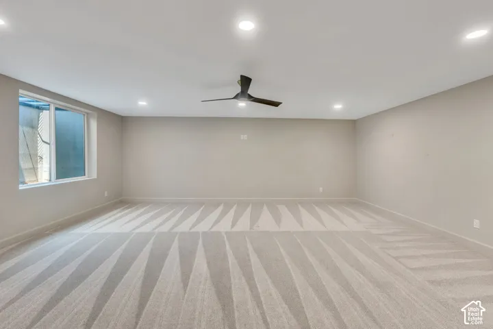 Spacious room featuring carpeting, recessed lighting, a contemporary ceiling fan, and a large window