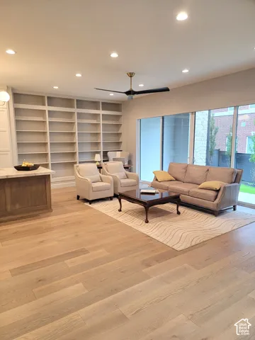 Built-in floor-to-ceiling shelving, light wood-finish flooring, recessed lighting, matte black ceiling fan, and expansive glass sliding doors