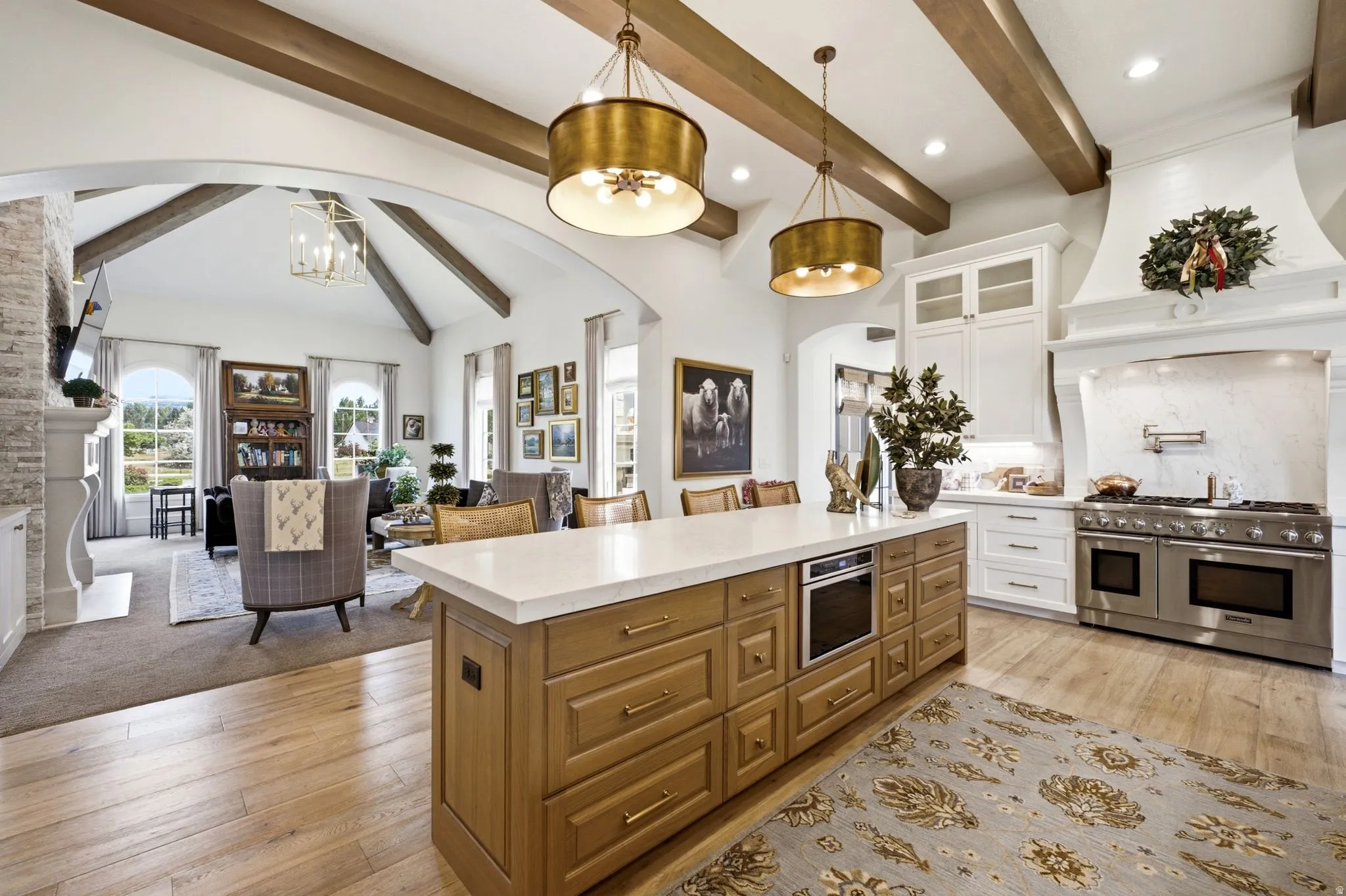 Gourmet kitchen featuring a large central island with integrated microwave, stainless steel professional-grade range with double ovens, custom range hood, and crisp white cabinetry