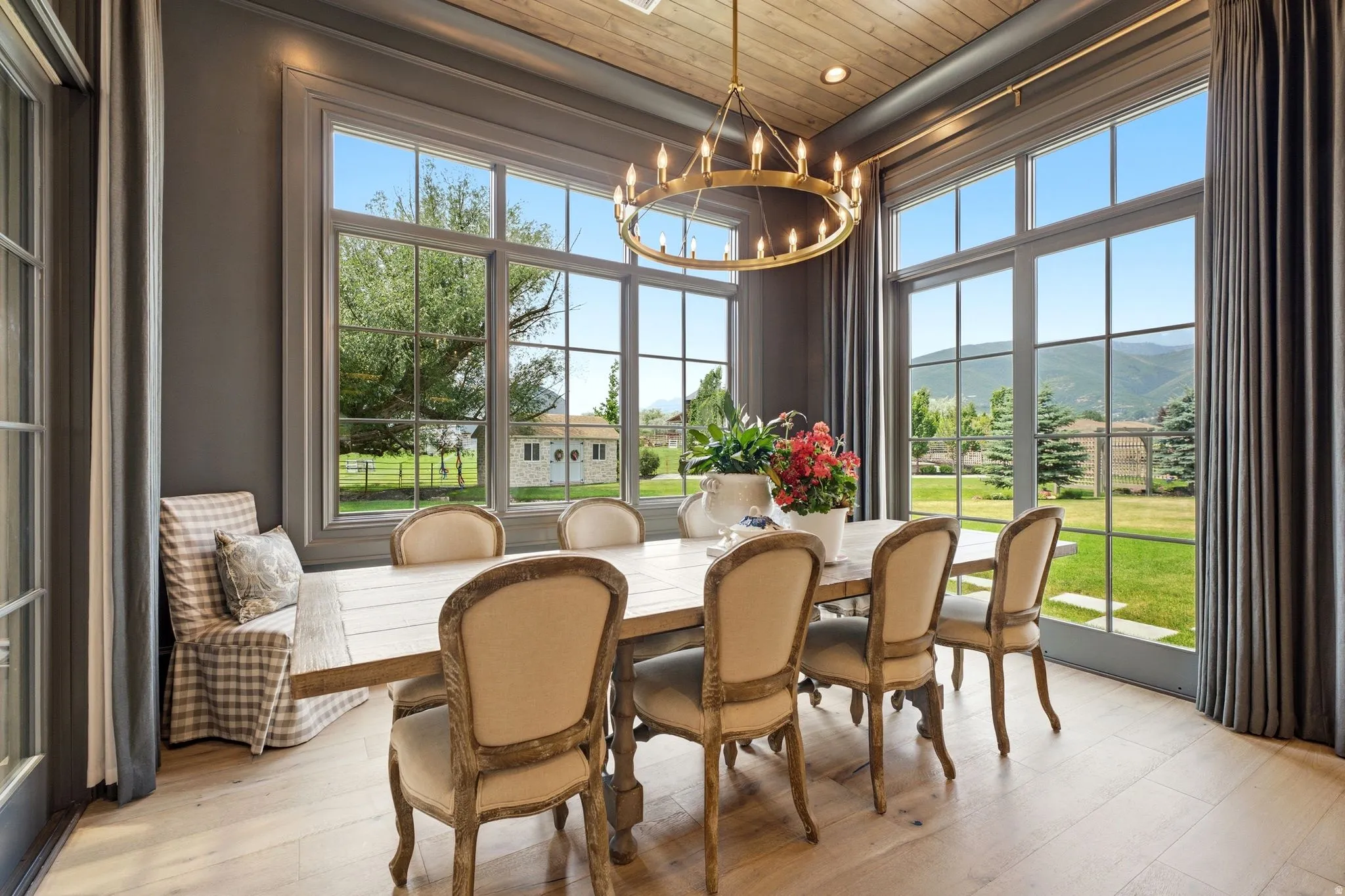 Dining space featuring expansive windows, light wood-finish flooring, a wood-paneled ceiling, and a large brass chandelier