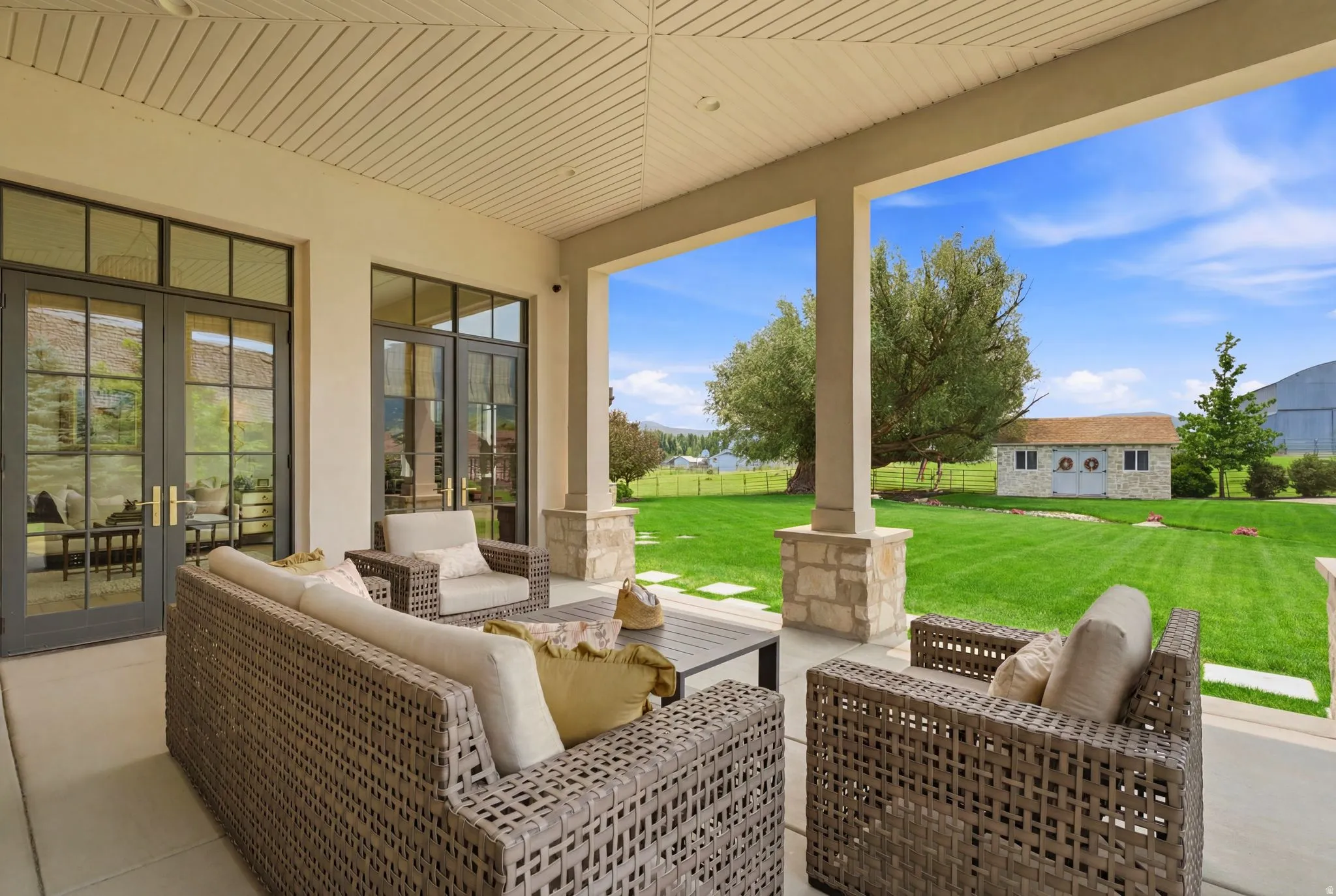 Covered patio with a slatted ceiling, stone-clad columns, and a concrete surface
