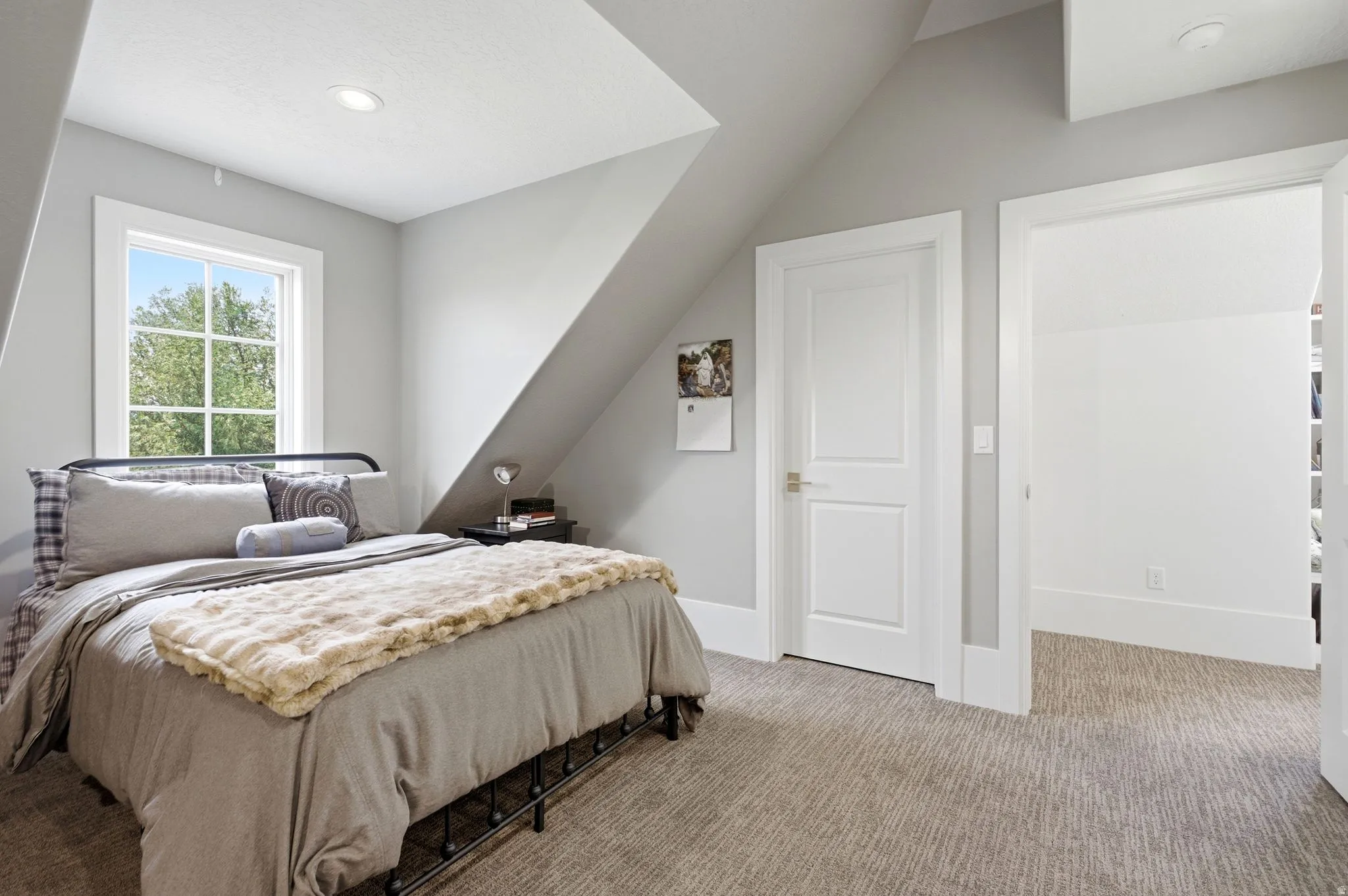 Carpeted room with a recessed light fixture and a window featuring white trim