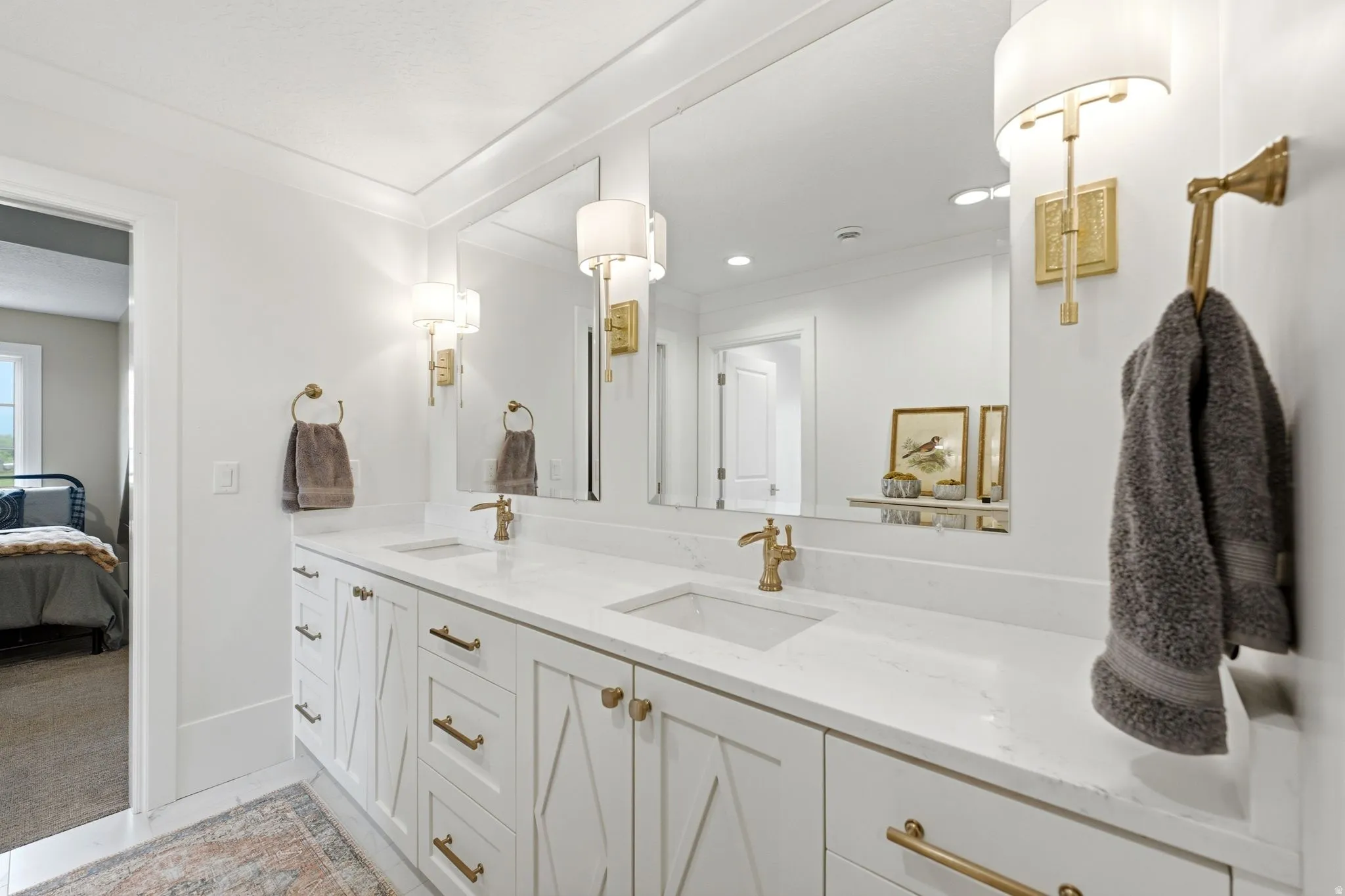 Dual vanity with white cabinetry, gold-finish hardware, and integrated sinks set into a white countertop