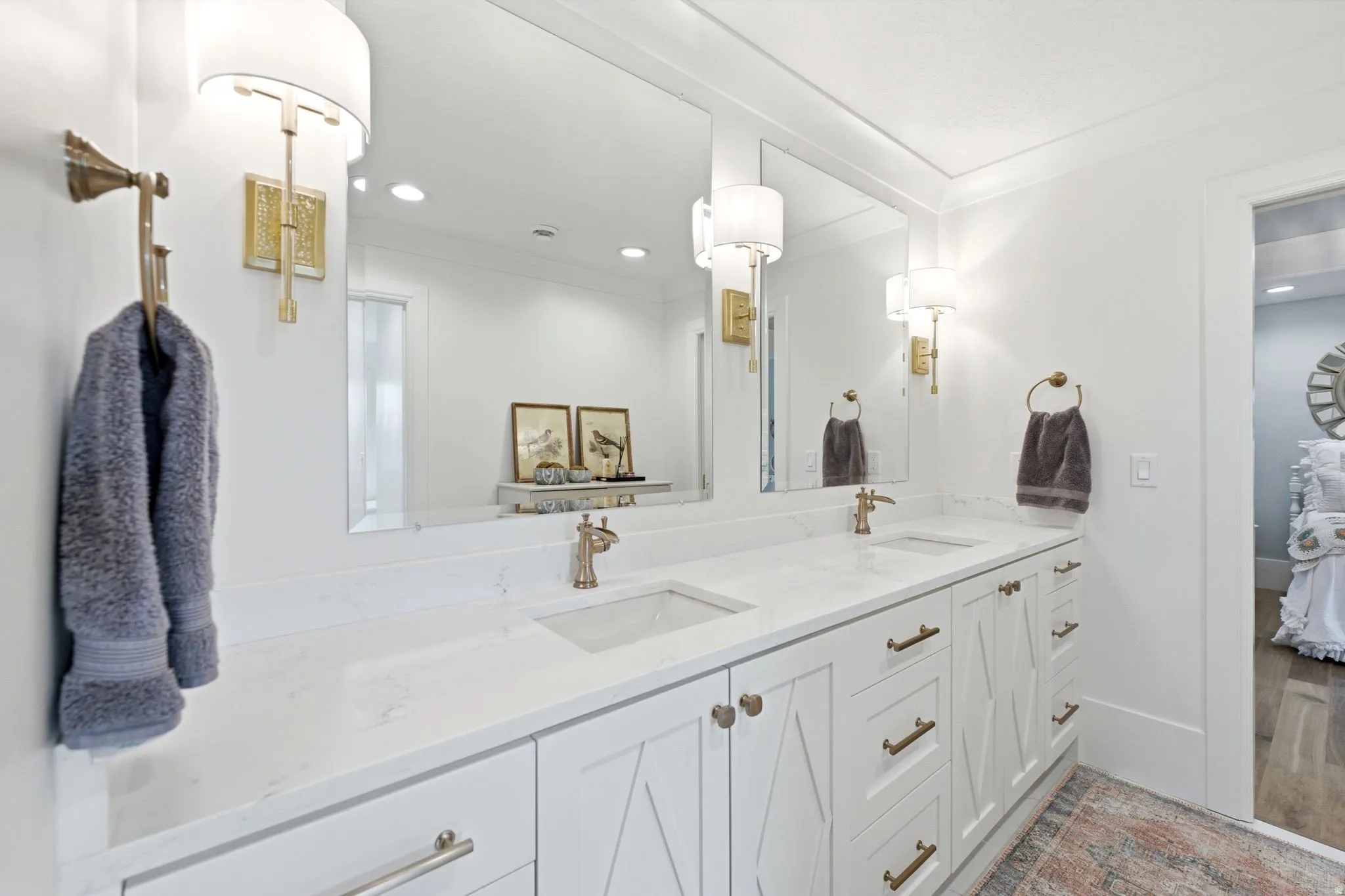 Dual vanity with white cabinetry and integrated sinks, complemented by polished hardware and wall-mounted sconces