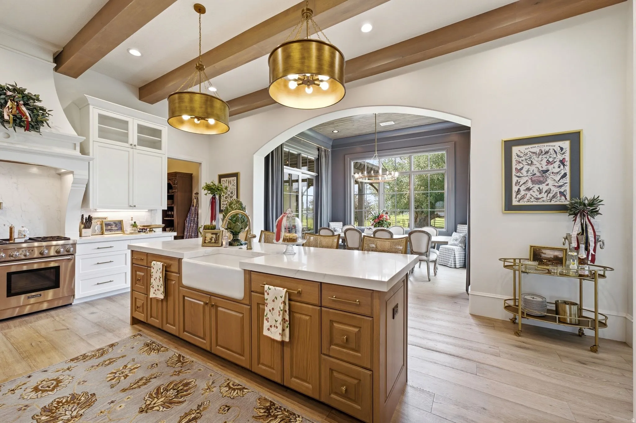 Gourmet kitchen featuring a wood-finish island with an integrated farmhouse sink, stainless steel range, and white cabinetry