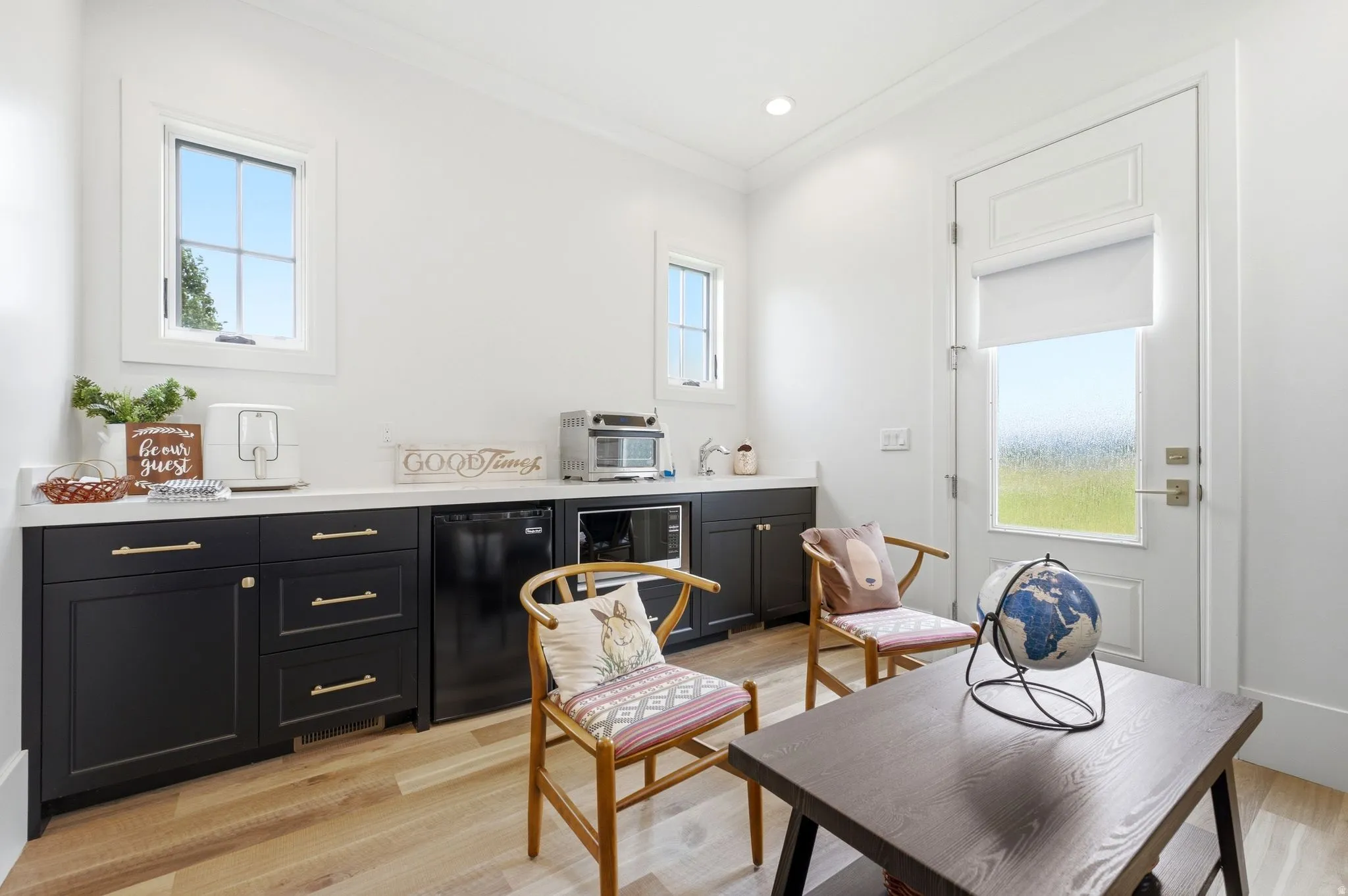 Integrated kitchenette featuring dark cabinetry with gold-tone hardware and white countertops