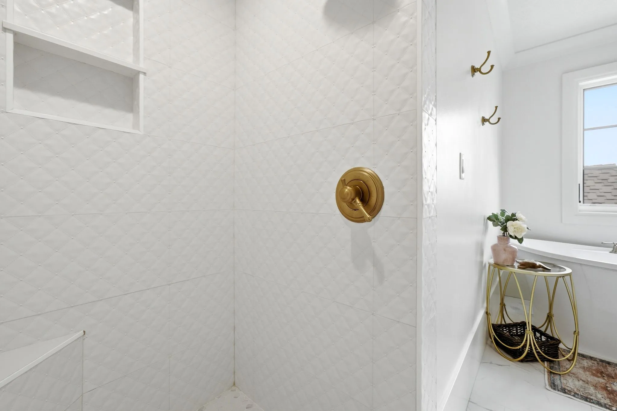 White tiled shower with a diamond pattern, featuring a built-in niche and a gold-finish shower control