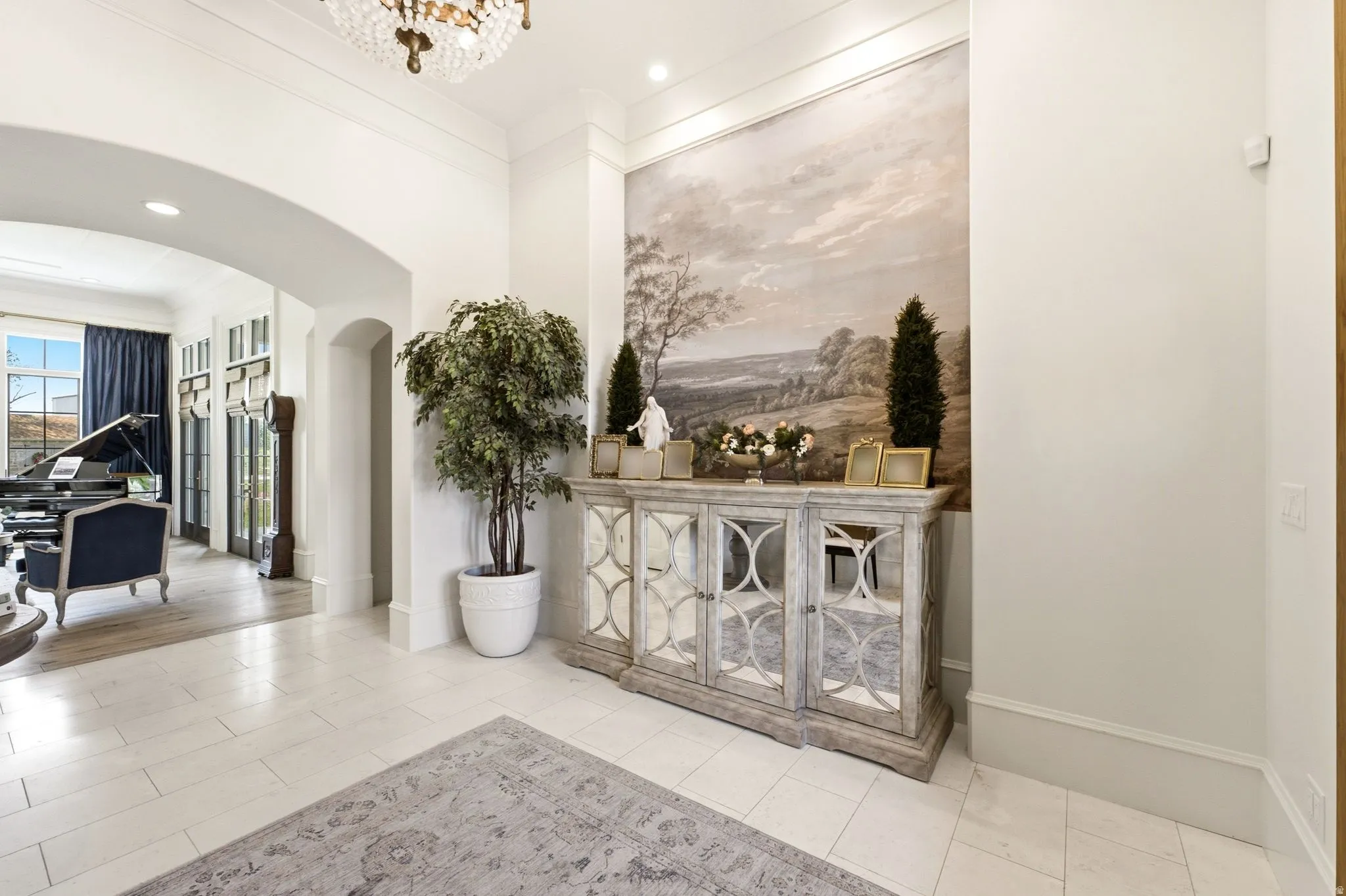 Grand entryway featuring high ceilings, a decorative chandelier, and light-toned tile flooring