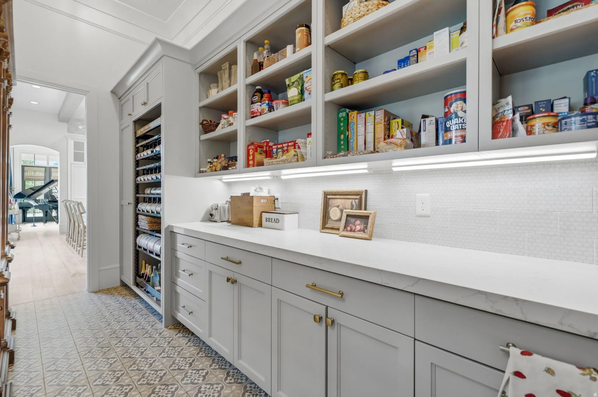 Custom pantry featuring extensive built-in shelving, a dedicated wine refrigeration unit, and a white countertop