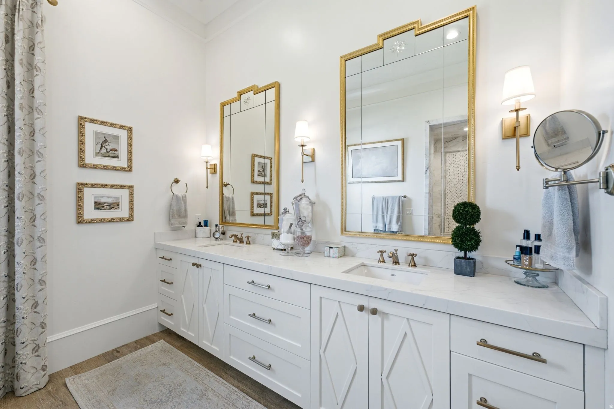 Double vanity featuring white cabinetry with brushed gold hardware, integrated sinks, and a stone countertop