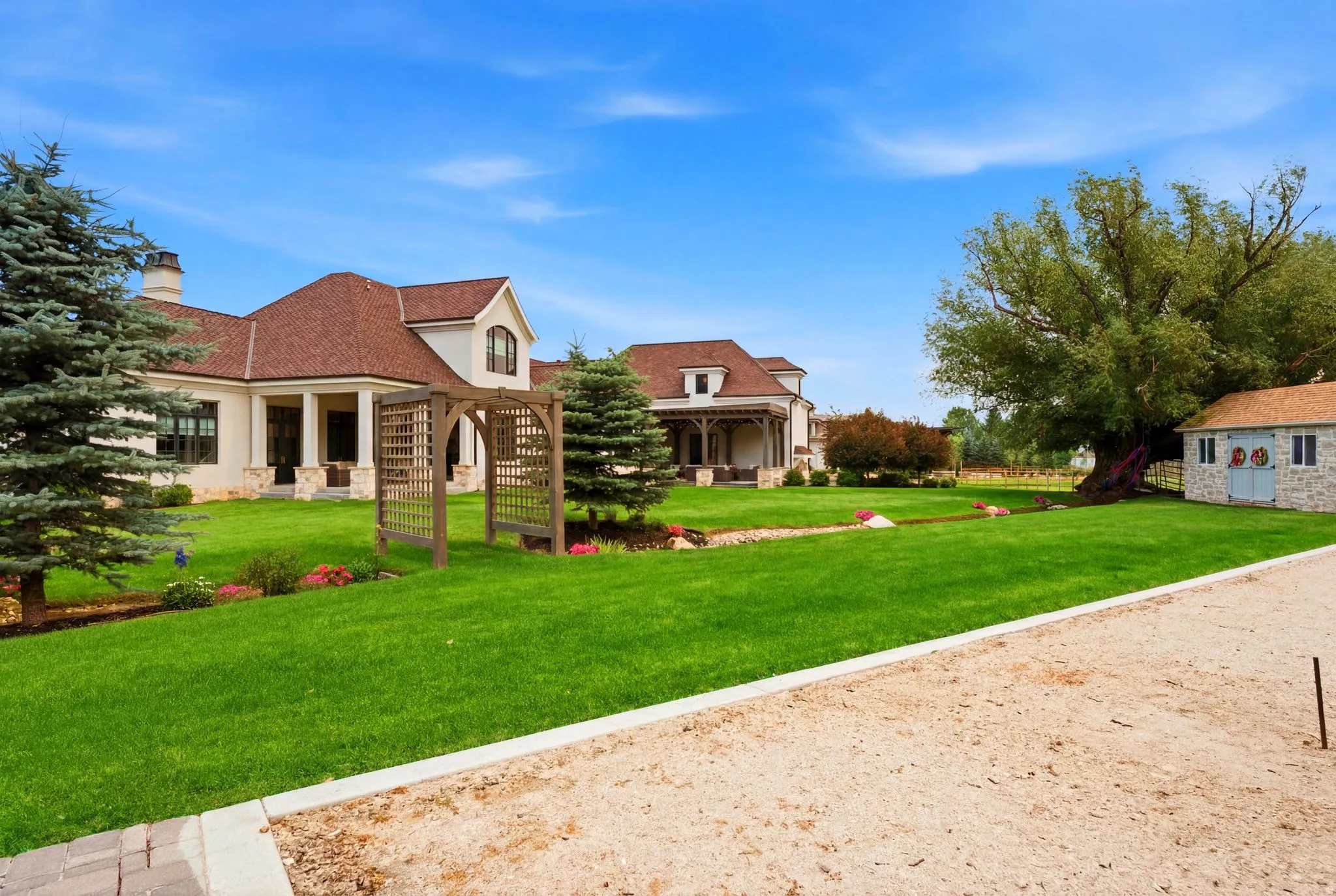Expansive green lawn with mature evergreen trees and a decorative wooden archway
