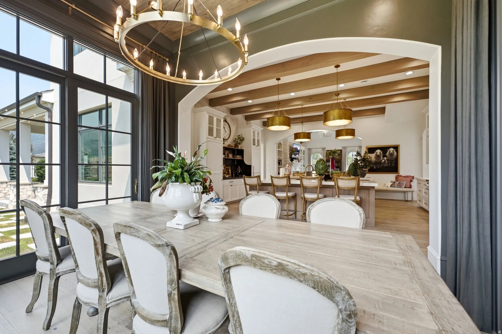 Dining area featuring a large wood-finish table, oversized chandelier with candelabra bulbs, and expansive black-framed windows