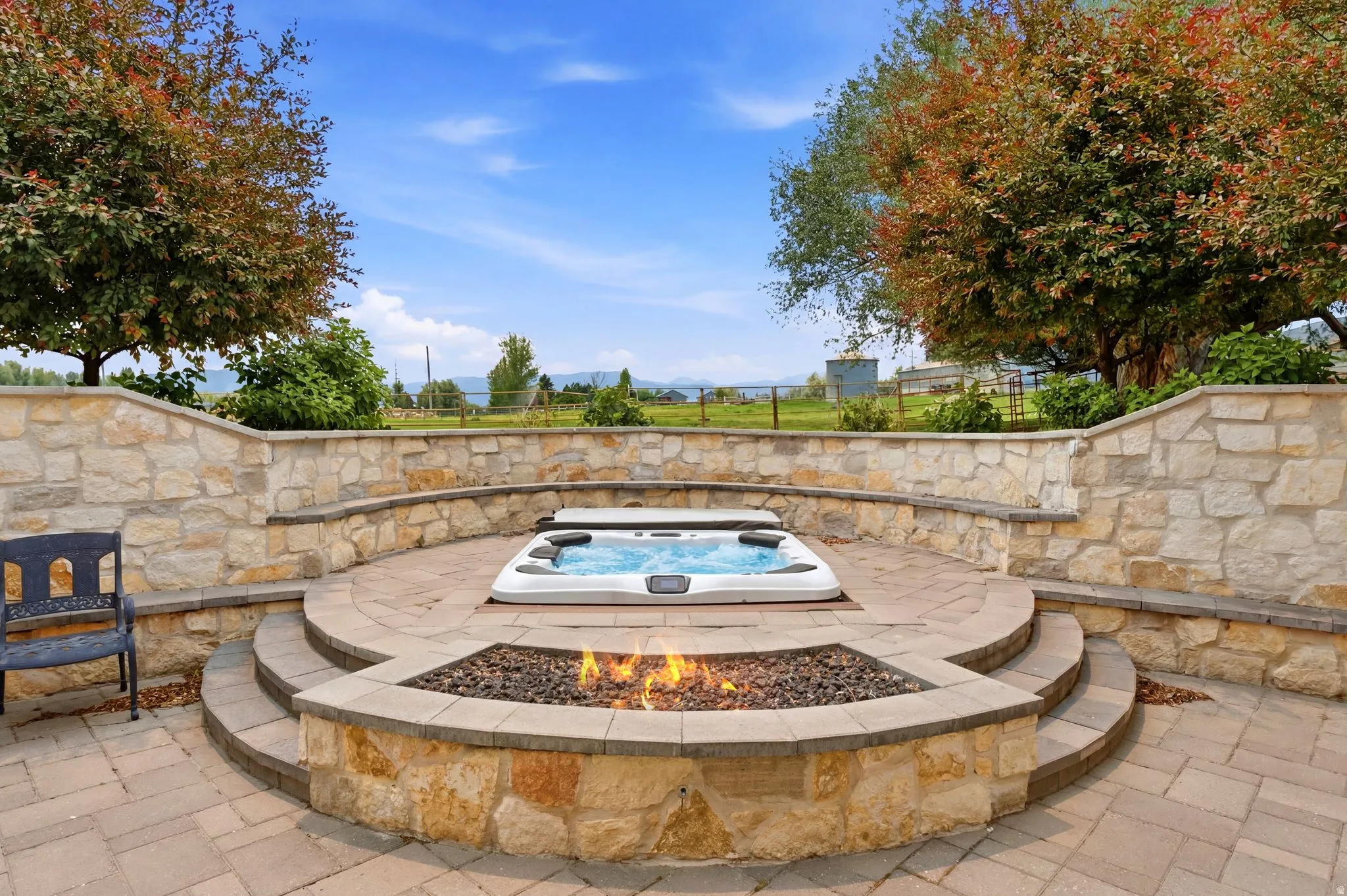 Expansive terraced patio featuring a built-in spa, a stone fire pit, and stone retaining walls