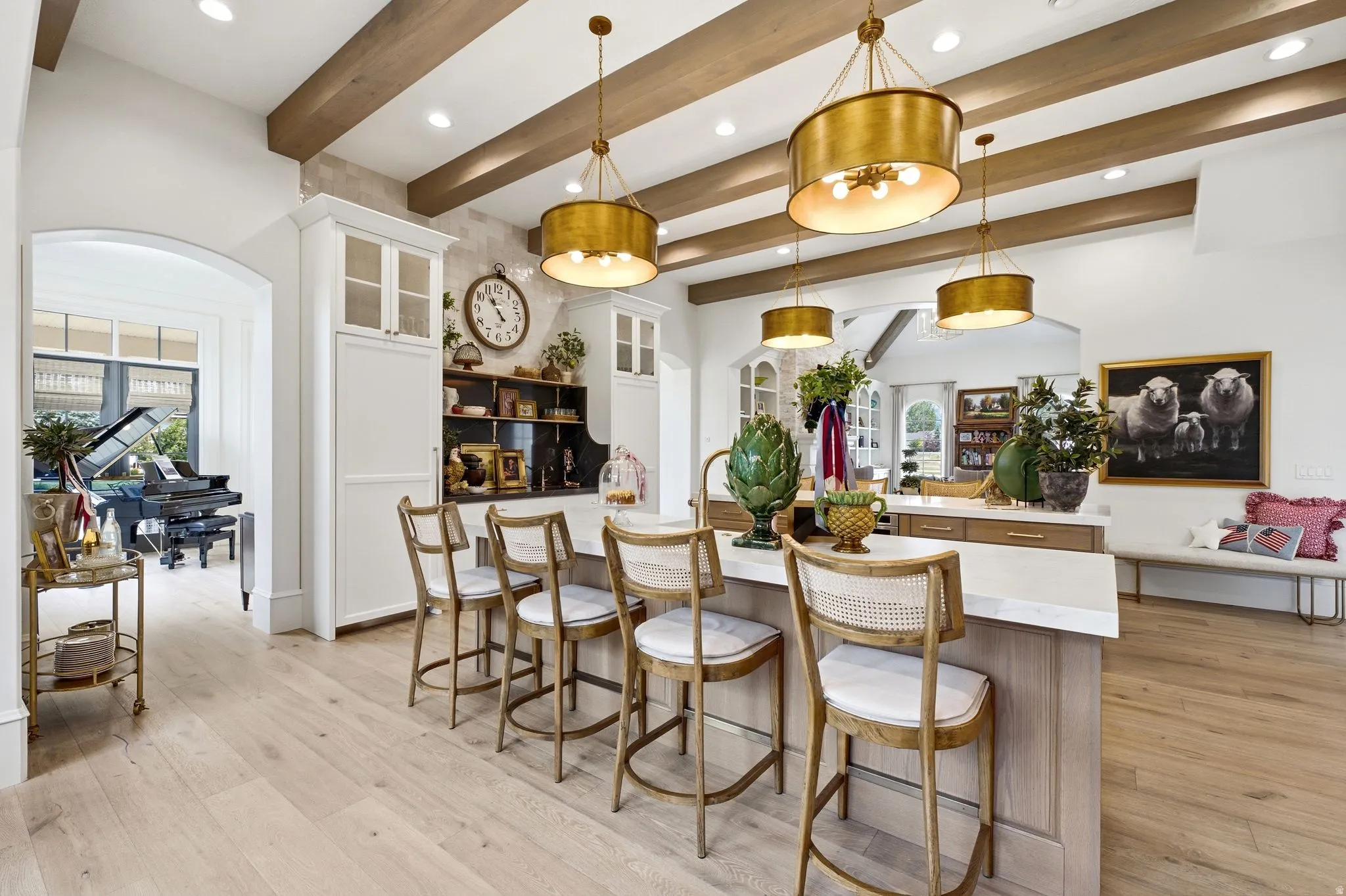 Gourmet kitchen featuring a substantial island with seating, integrated cabinetry, wood-finish flooring, exposed ceiling beams, and recessed lighting
