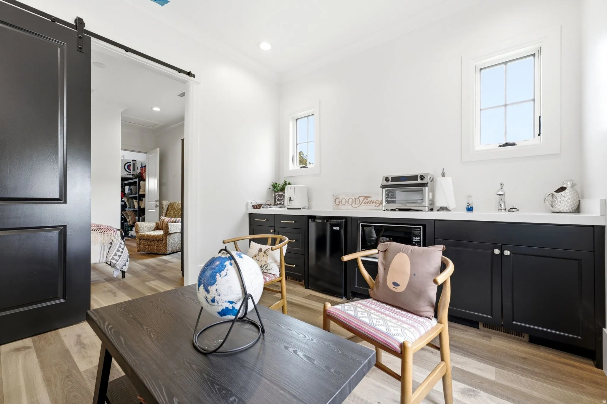 Room with wood-finish flooring, a black barn door, and white walls
