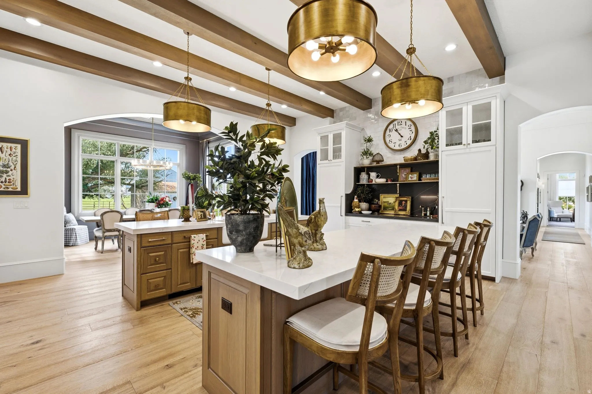 Open-concept kitchen featuring two islands with stone countertops, a beamed ceiling, and wood-finish flooring