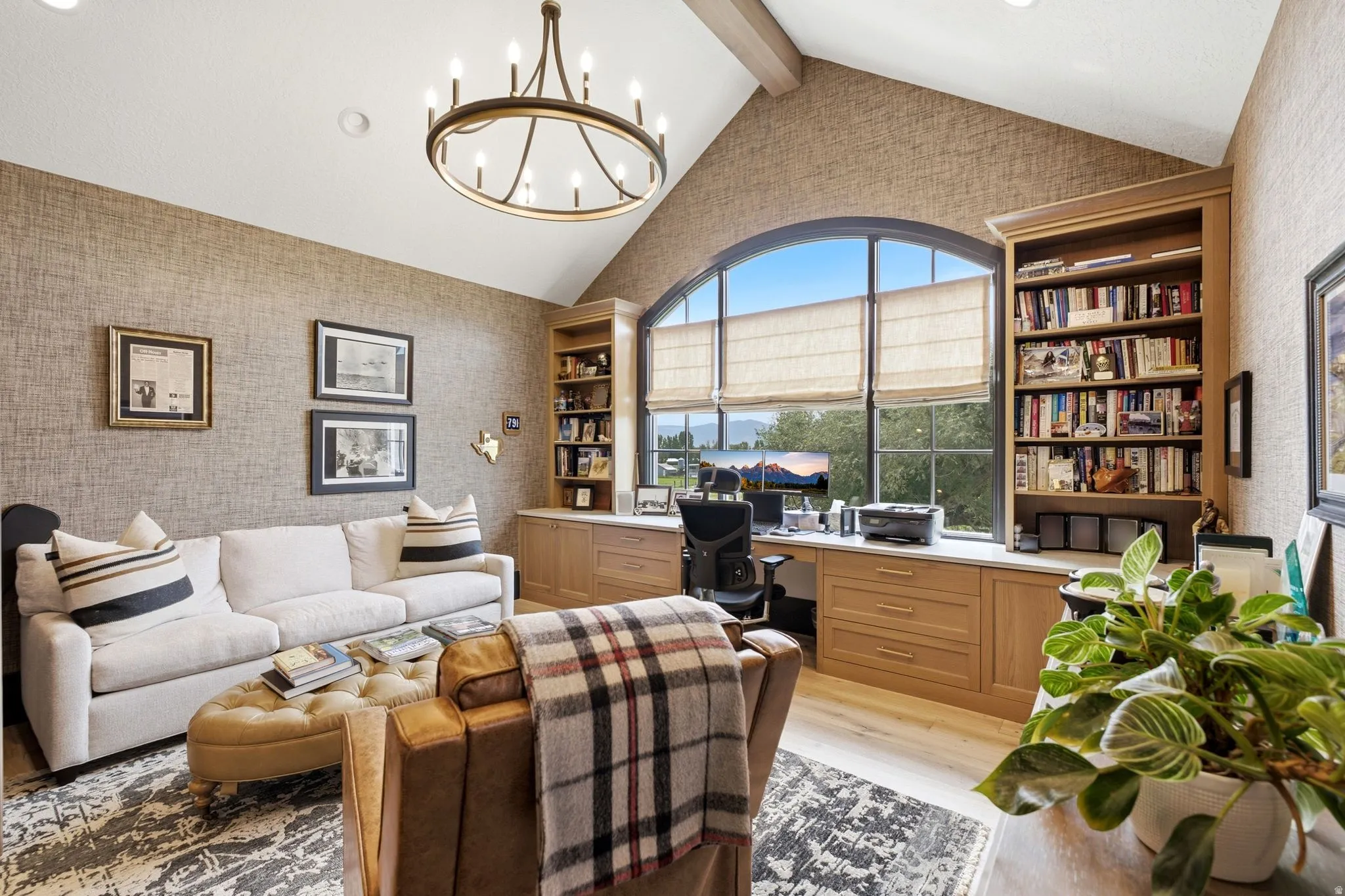 Room with vaulted ceilings and exposed beam, featuring a large arched window