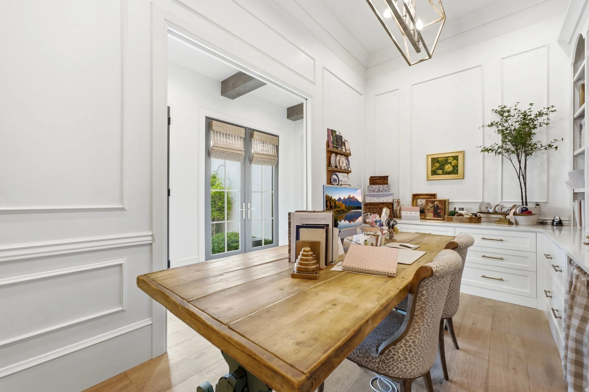Dedicated room featuring light wood-finish flooring, white paneled walls, and built-in cabinetry with marble-look countertops