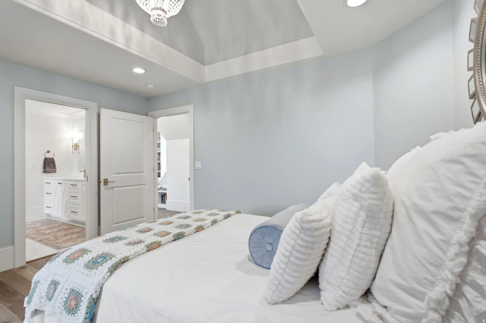 Vaulted ceiling with an elegant chandelier, recessed lighting, and wood-finish flooring