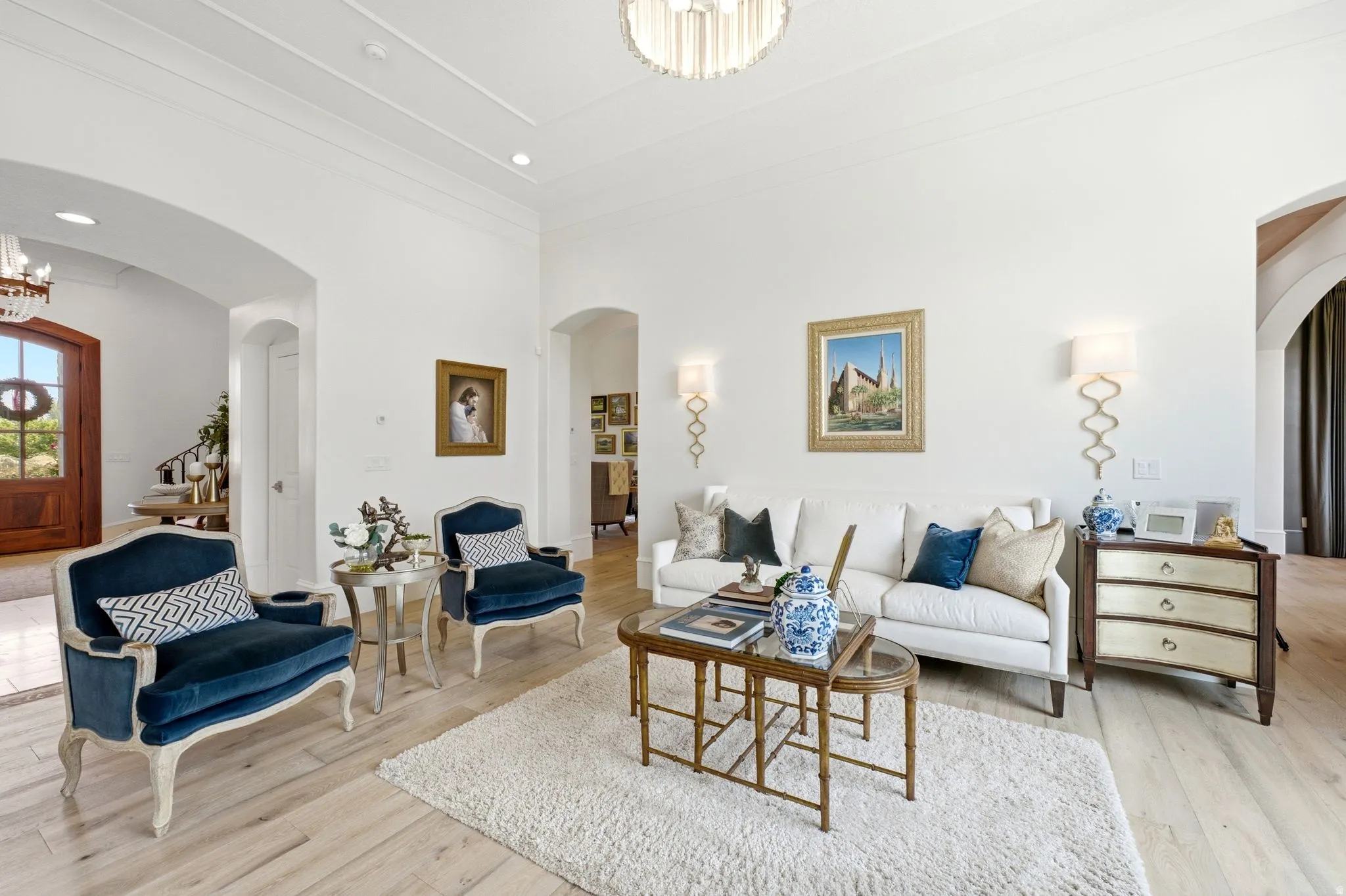 Spacious living area featuring light wood-finish flooring and high ceilings with decorative trim
