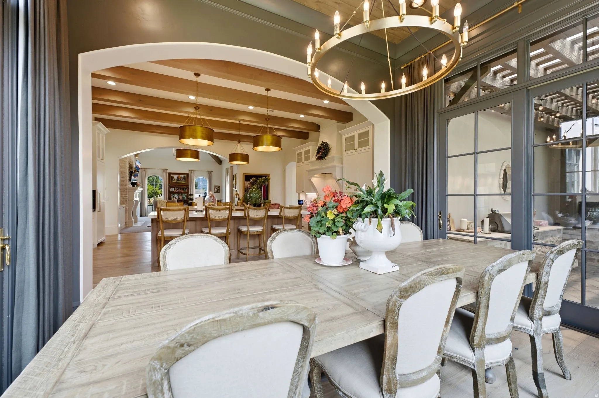Dining area featuring a large distressed wood-finish table, a gold-tone chandelier, and multiple paneled glass doors