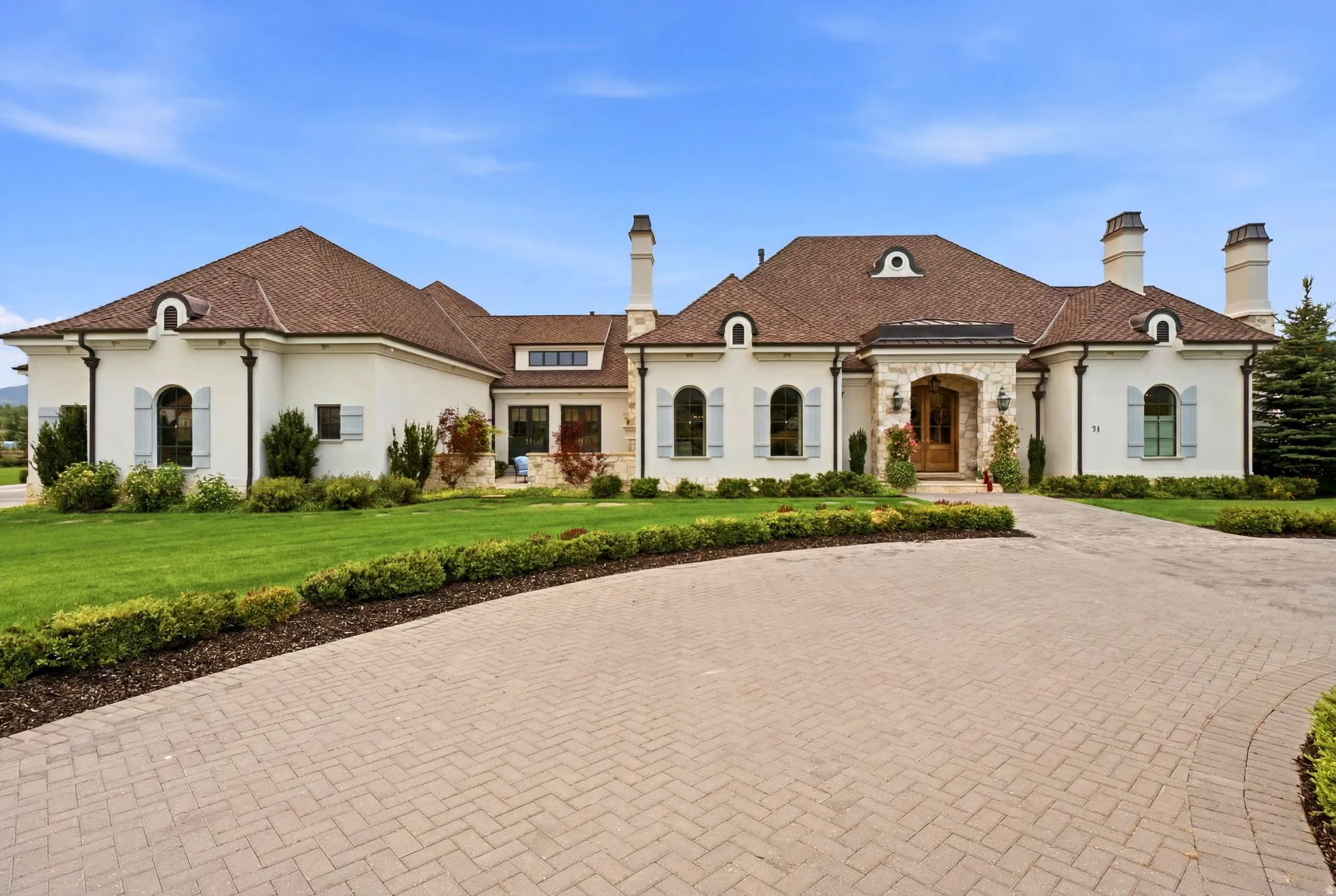 Stately exterior with a stucco finish, stone accents, and a brown tile roof