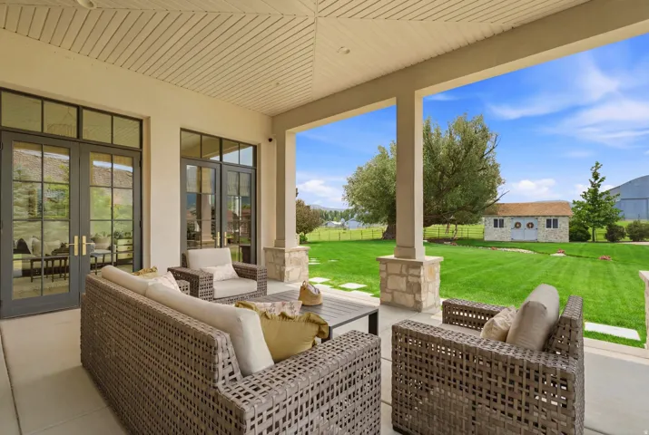 Covered patio with a slatted ceiling, stone-clad columns, and a concrete surface
