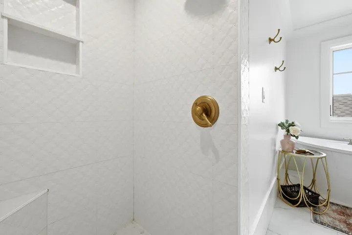 White tiled shower with a diamond pattern, featuring a built-in niche and a gold-finish shower control