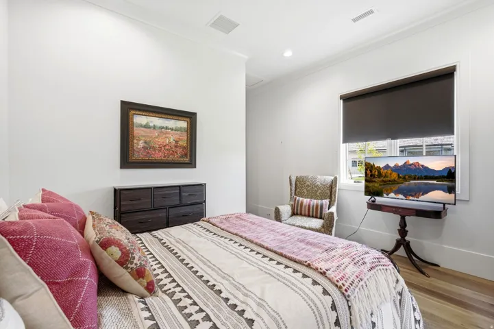 Bedroom featuring a window with roller shade, recessed lighting, and wood-finish flooring