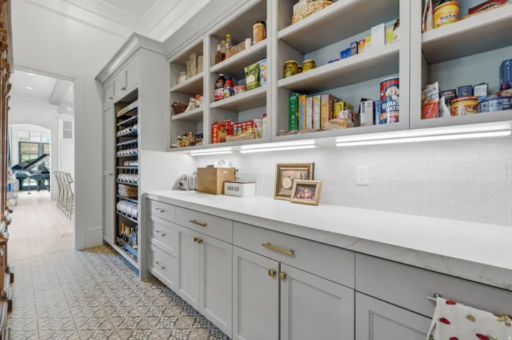 Custom pantry featuring extensive built-in shelving, a dedicated wine refrigeration unit, and a white countertop
