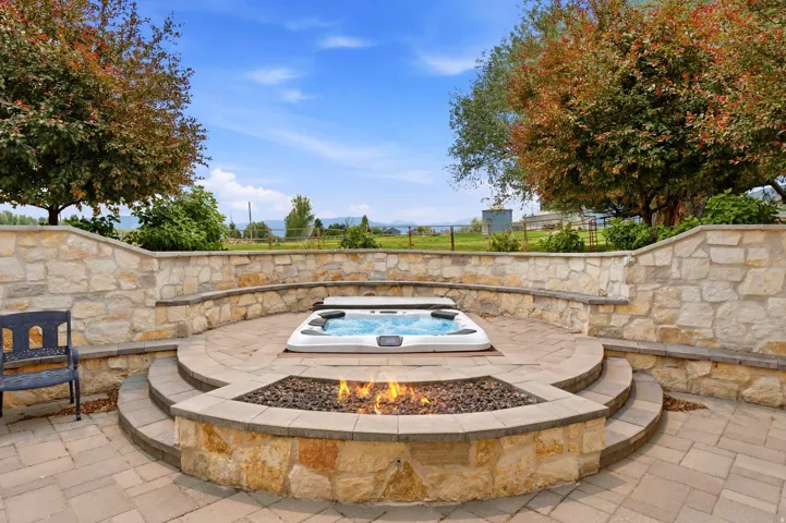 Expansive terraced patio featuring a built-in spa, a stone fire pit, and stone retaining walls