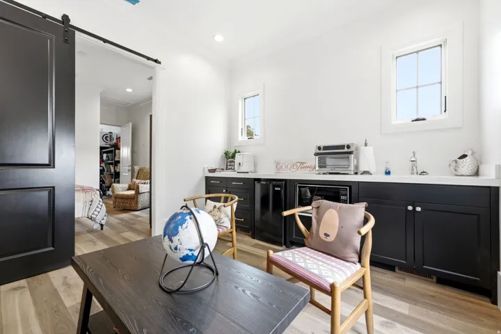 Room with wood-finish flooring, a black barn door, and white walls