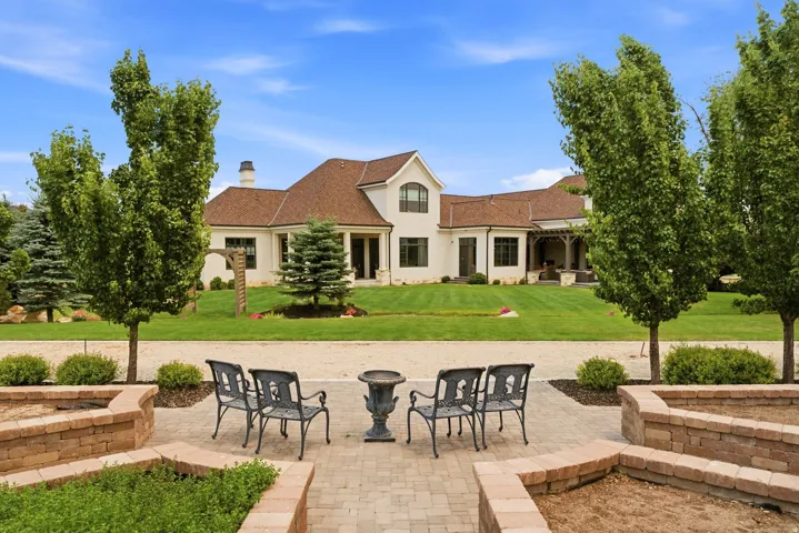 Expansive outdoor patio area featuring paver flooring, curved brick planters, and mature trees