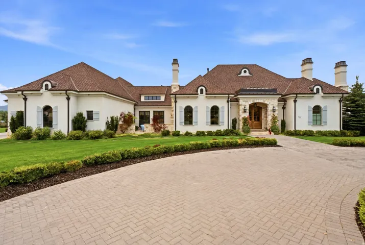 Stately exterior with a stucco finish, stone accents, and a brown tile roof