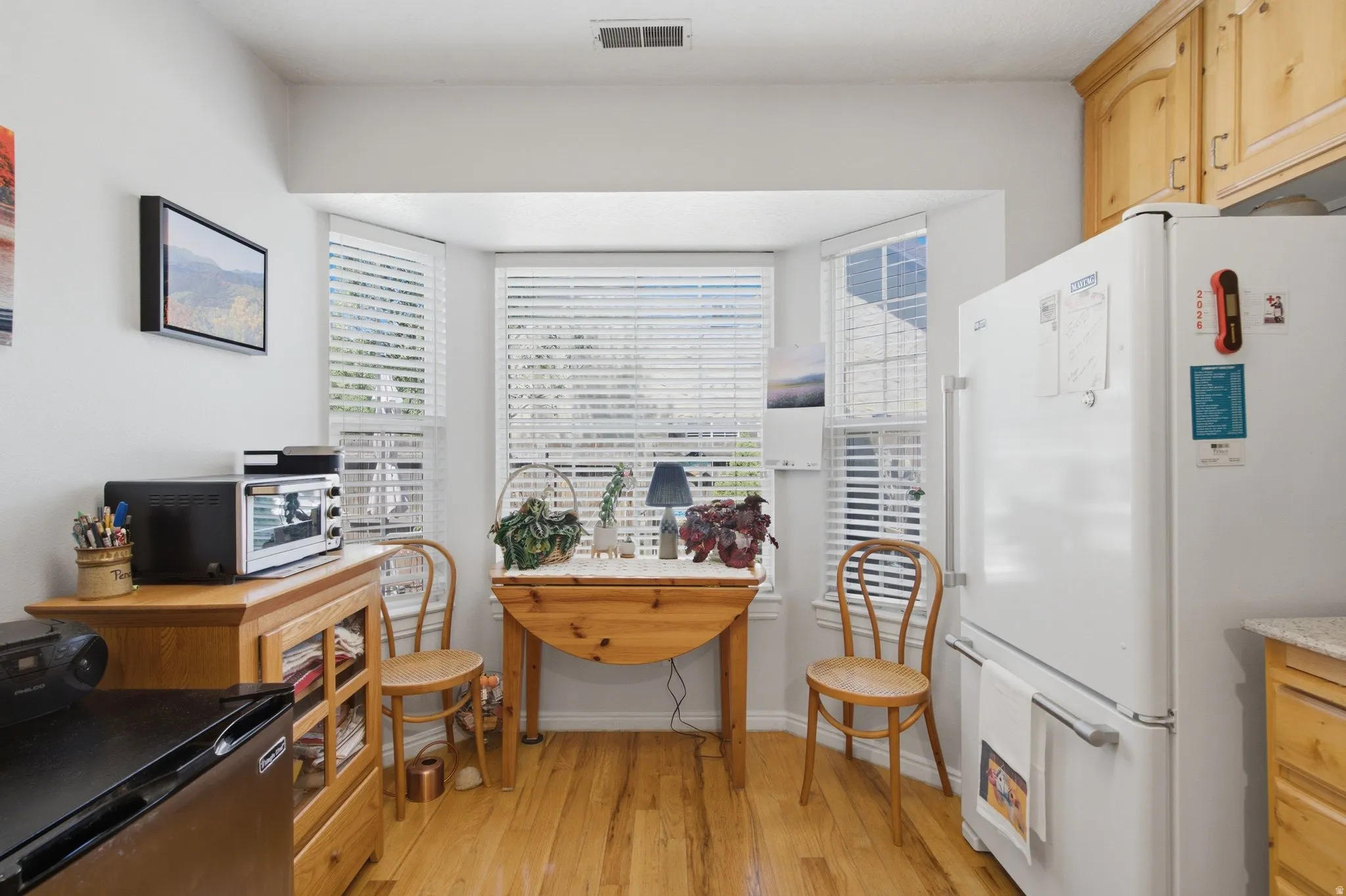 Bay window with natural light, wood-finish flooring, and light-toned cabinetry
