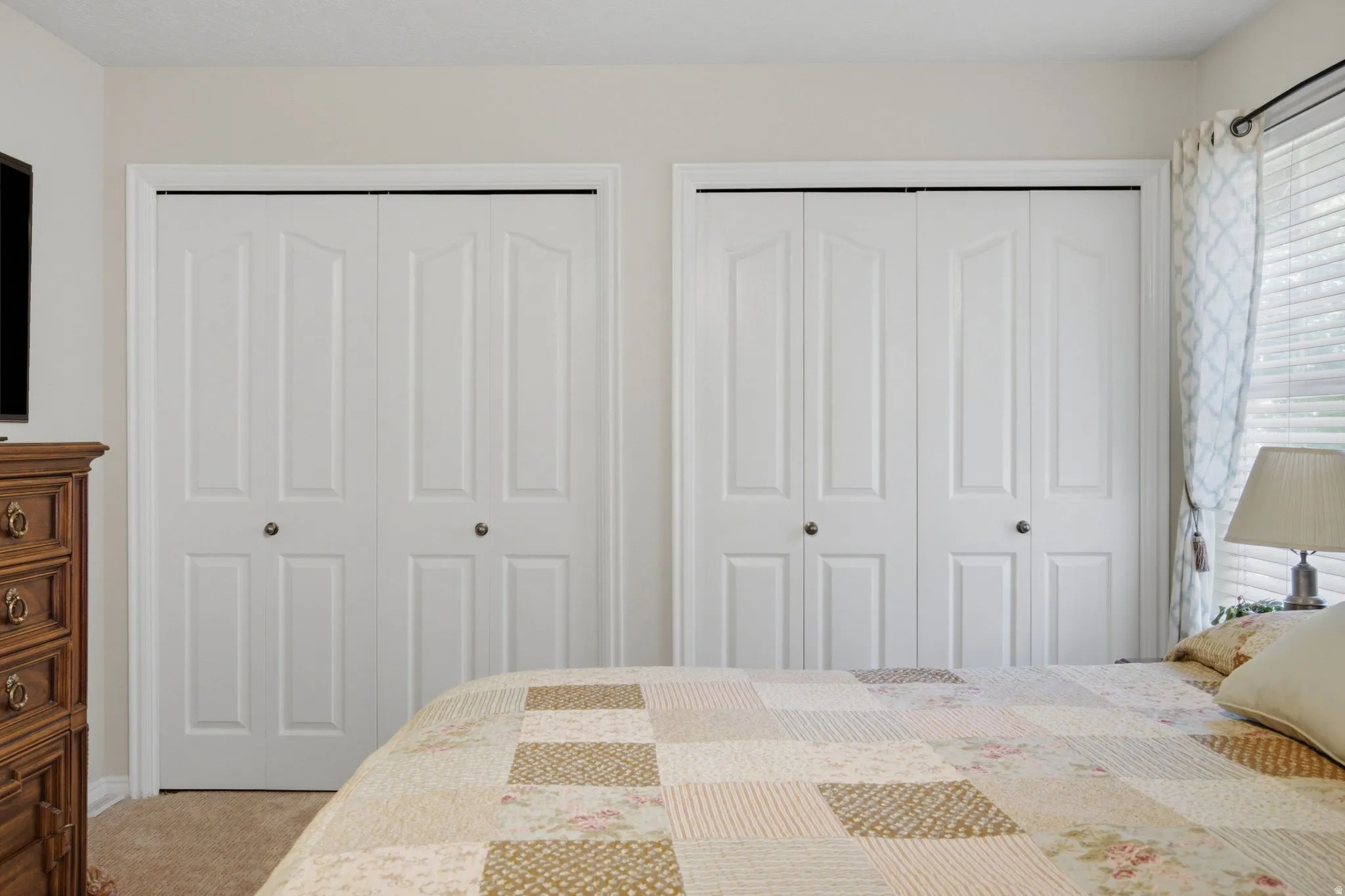 Two sets of white bifold closet doors with panel detailing, set against light-colored walls